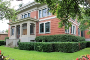 A photograph of City Hall with hedges around the side and a green lawn