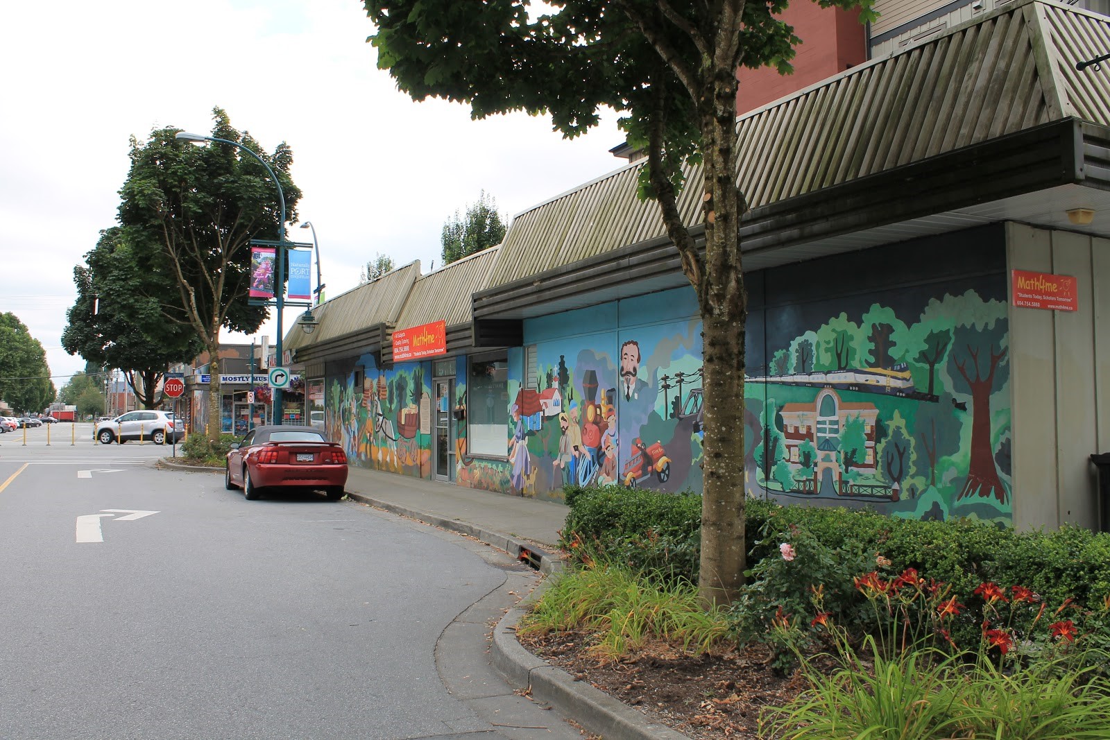 A photo of a line of shops with the colourful Span of Time mural along the side.