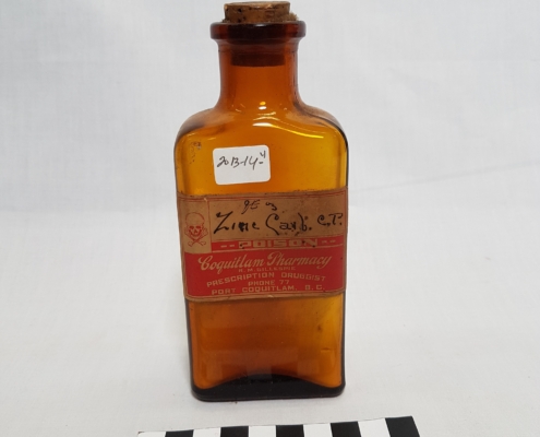 A light brown glass bottle with cork stopper and faded pharmacy label