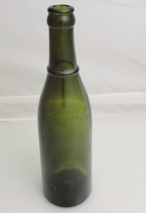 A dark green glass wine bottle with embossed text in English and Chinese sits on a table