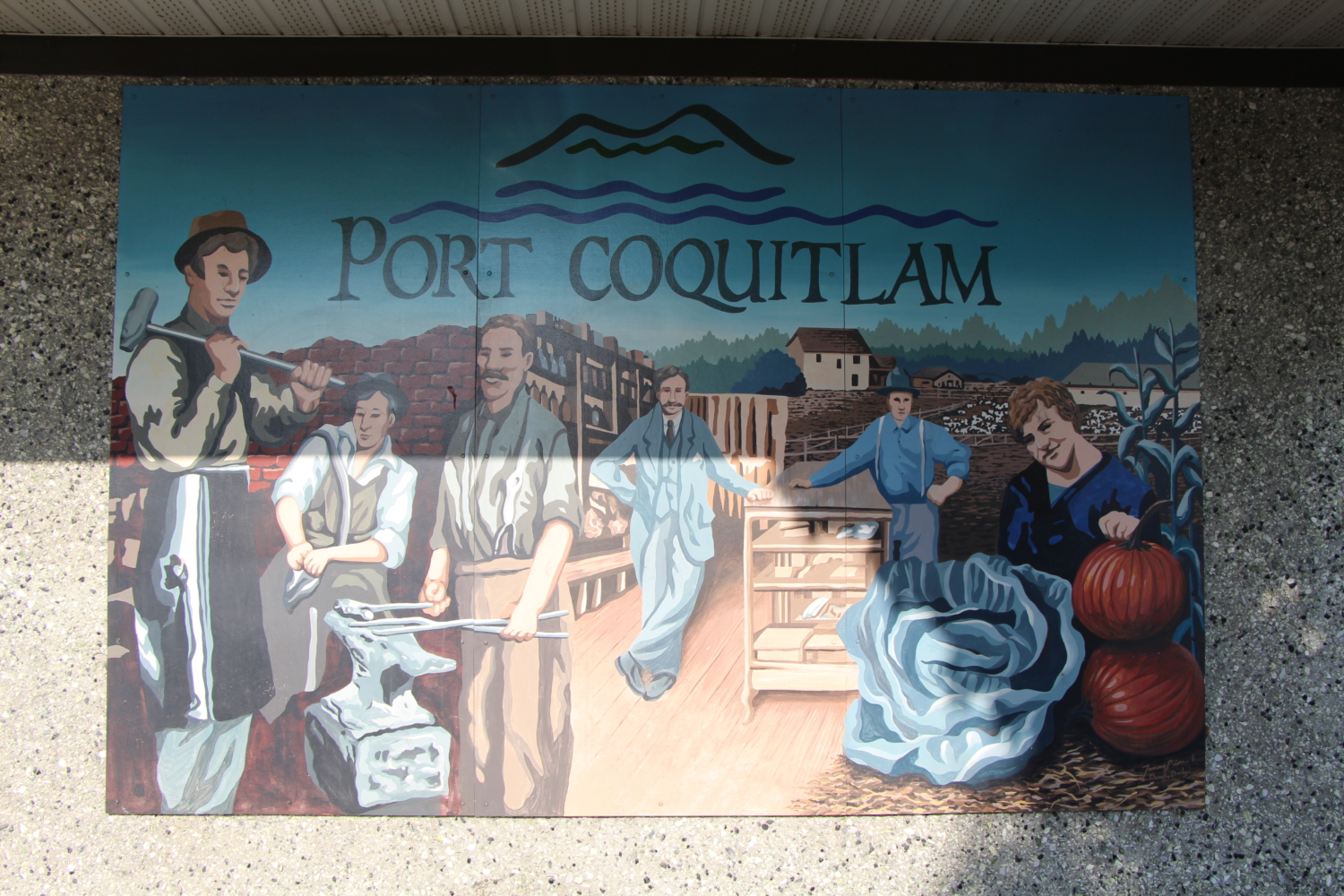 A photo of the pioneer mural on a stucco wall. It depicts early PoCo businesses like the blacksmith, general store, and farms, and has the title "Port Coquitlam."