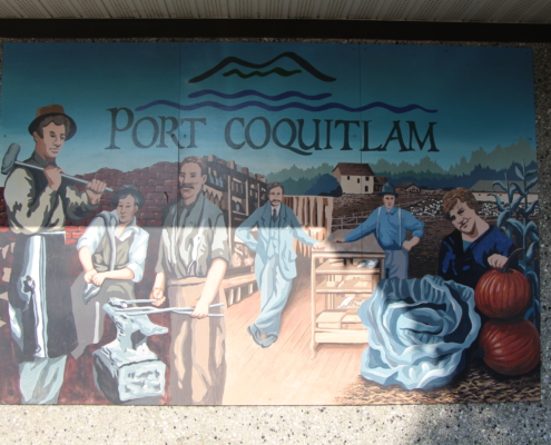 A photo of the pioneer mural on a stucco wall. It depicts early PoCo businesses like the blacksmith, general store, and farms, and has the title "Port Coquitlam."